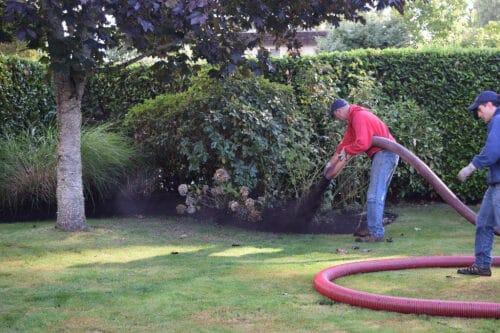 man blowing compost on a lawn